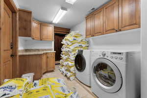 Laundry area featuring independent washer and dryer, cabinets, and light tile patterned flooring