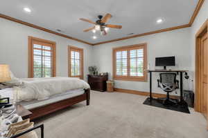 Carpeted bedroom with ceiling fan and ornamental molding