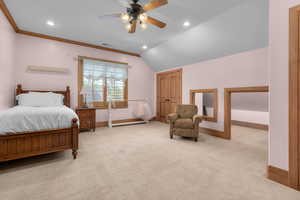 Carpeted bedroom with crown molding, lofted ceiling, and ceiling fan