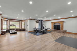 Exercise room featuring ornamental molding, a brick fireplace, and light hardwood / wood-style floors