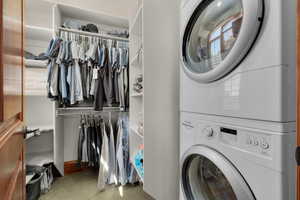 Clothes washing area with stacked washer / dryer and light carpet