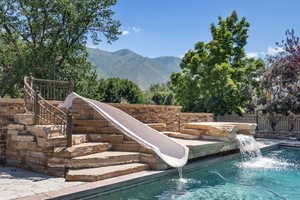 View of pool featuring pool water feature, a water slide, and a mountain view