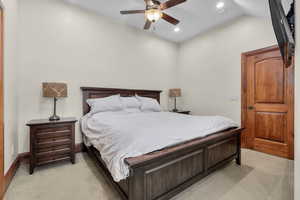 Bedroom with lofted ceiling, ceiling fan, and light colored carpet