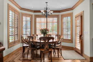 Dining space with hardwood / wood-style flooring, a notable chandelier, and ornamental molding