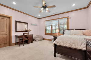 Carpeted bedroom with ceiling fan and crown molding