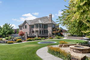 Rear view of property featuring a fire pit and a lawn