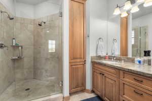 Bathroom featuring tile patterned flooring, a shower with door, and vanity