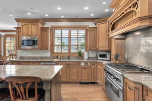 Kitchen featuring a wealth of natural light, stainless steel appliances, light hardwood / wood-style floors, and ornamental molding