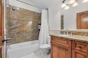 Full bathroom with tile patterned floors, shower / bath combination with curtain, toilet, and vanity