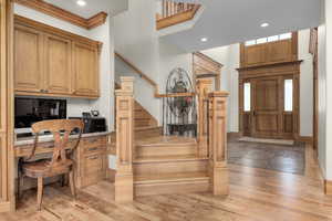 Foyer entrance featuring built in desk, hardwood / wood-style floors, and crown molding