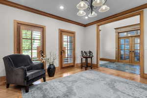 Living area with crown molding, a wealth of natural light, and wood-type flooring