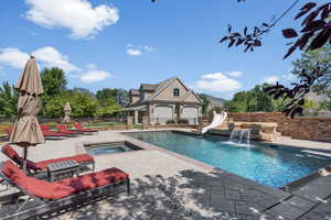 View of pool featuring a water slide, an in ground hot tub, and a patio area