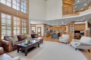 Living room featuring ornamental molding, light hardwood / wood-style flooring, a chandelier, and a high ceiling