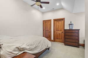 Carpeted bedroom with lofted ceiling and ceiling fan