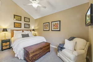 Carpeted bedroom with vaulted ceiling and ceiling fan