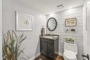 Bathroom featuring toilet, hardwood / wood-style flooring, a textured ceiling, and vanity