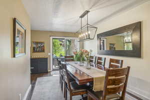 Dining area with dark hardwood / wood-style flooring, a notable chandelier, and a textured ceiling