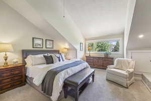 Bedroom with light carpet and lofted ceiling