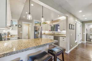 Kitchen with dark hardwood / wood-style flooring, stainless steel appliances, sink, and white cabinetry