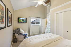 Bedroom with light colored carpet, ceiling fan, a closet, and high vaulted ceiling