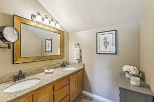 Bathroom with vaulted ceiling, a textured ceiling, and vanity