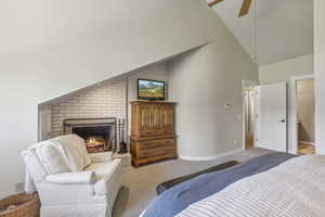 Bedroom with a fireplace, light colored carpet, high vaulted ceiling, and ceiling fan