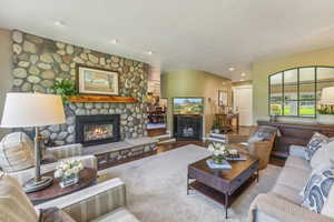 Living room with a textured ceiling, a stone fireplace, and hardwood / wood-style flooring