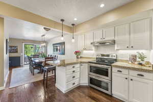 Kitchen with white cabinets, pendant lighting, electric stove, and dark hardwood / wood-style flooring