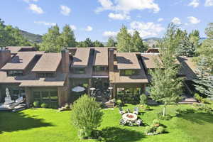 Rear view of property with a mountain view, a lawn, and an outdoor fire pit