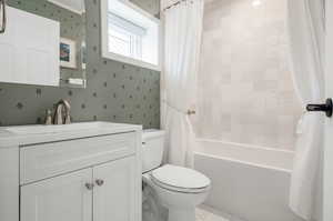 Full bathroom featuring toilet, shower / tub combo with curtain, and vanity