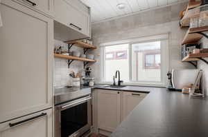 Kitchen with white cabinets, tasteful backsplash, stainless steel oven, and sink