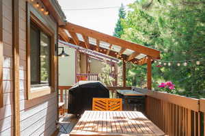 Wooden terrace featuring a hot tub and area for grilling