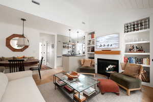 Living room featuring high vaulted ceiling, built in features, light hardwood / wood-style flooring, sink, and wood ceiling