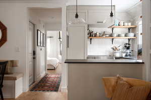 Kitchen with decorative light fixtures, backsplash, kitchen peninsula, lofted ceiling, and light wood-type flooring