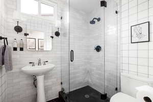 Bathroom with tile walls, toilet, and a shower with door