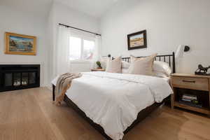 Bedroom with light wood-type flooring and lofted ceiling