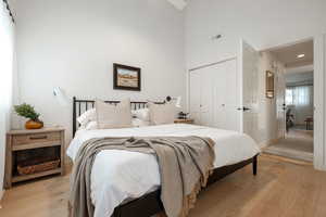 Bedroom featuring light wood-type flooring, a closet, and a high ceiling