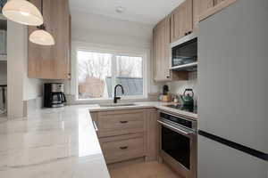 Kitchen featuring appliances with stainless steel finishes, light brown cabinetry, light hardwood / wood-style flooring, and sink