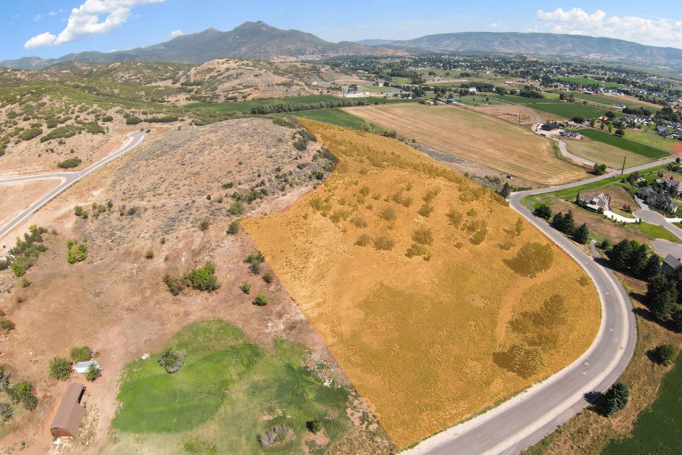Expansive parcel featuring a paved road frontage, natural landscaping, varied topography, and mountainous backdrops