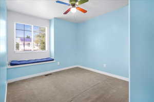 Spare room featuring ceiling fan and carpet