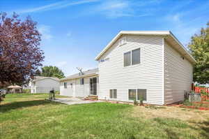 Rear view of property with a yard and a patio