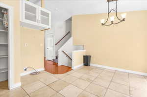 Interior space featuring vaulted ceiling, light tile patterned floors, and a chandelier