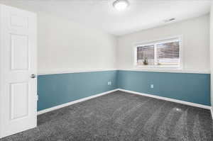 Carpeted empty room featuring a textured ceiling