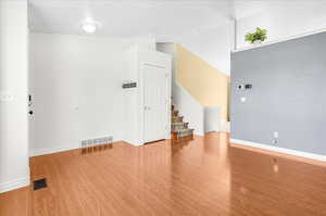 Empty room with vaulted ceiling and hardwood / wood-style floors