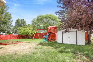 View of yard with a playground and a shed