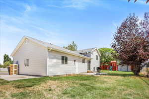 Rear view of house with a patio area, a lawn, and a storage unit