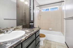 Full bathroom with toilet, tile patterned flooring, vanity, tiled shower / bath combo, and decorative backsplash