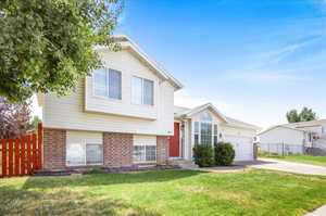 Split level home featuring a garage and a front lawn