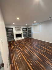 Unfurnished living room with dark hardwood / wood-style flooring and a brick fireplace