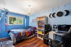 Bedroom with dark wood-type flooring and a chandelier